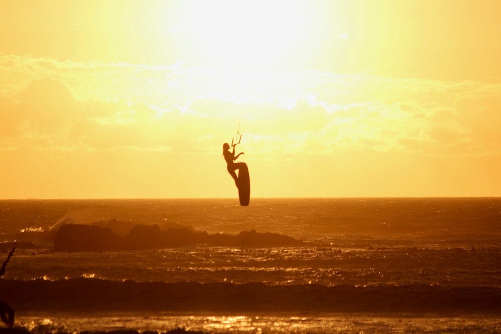 eine Person auf einem Surfbrett in der Luft über dem Ozean