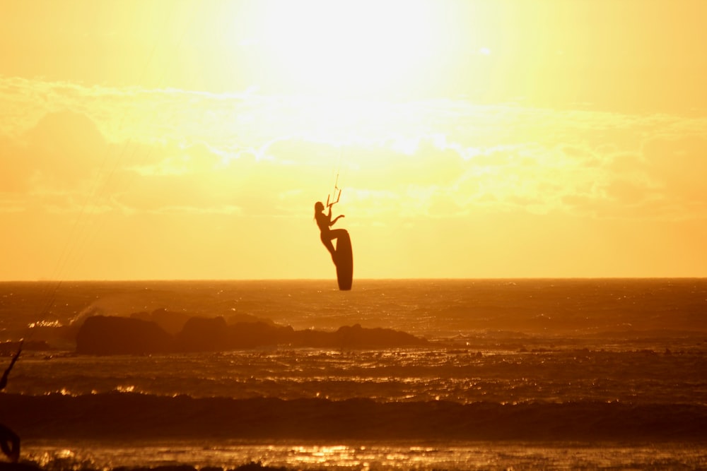 una persona en una tabla de surf en el aire sobre el océano