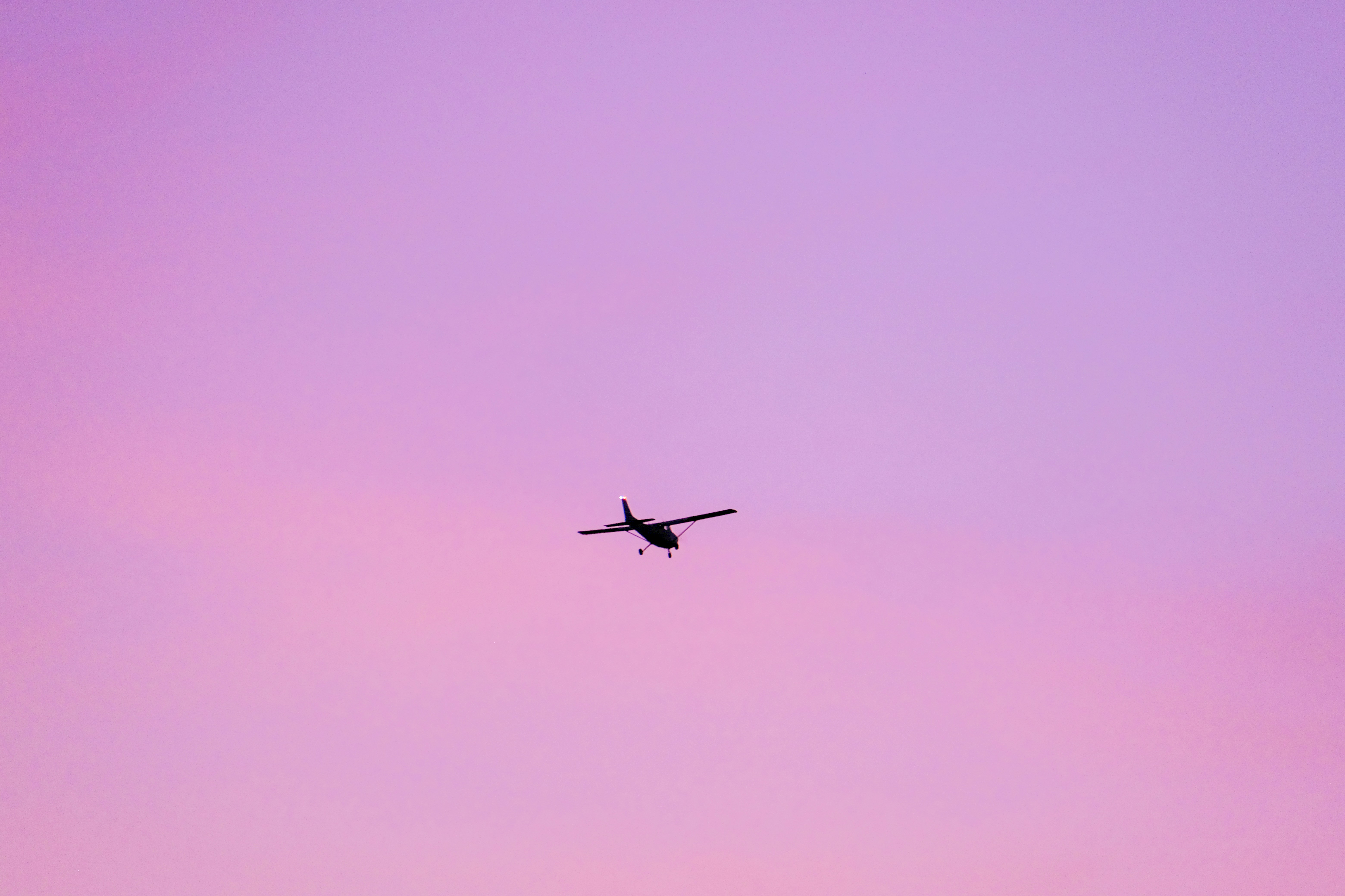 a plane flying in the sky at sunset