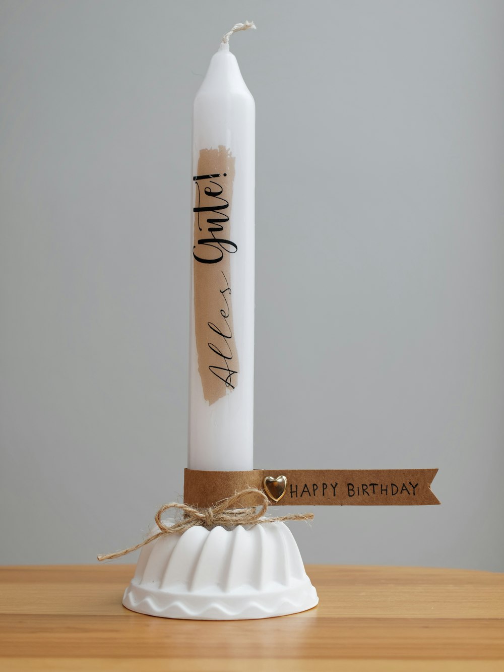 a white candle with a brown ribbon around it