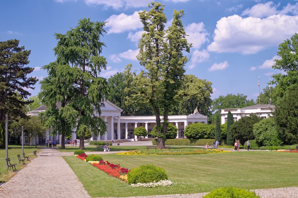 a large white building sitting next to a lush green park