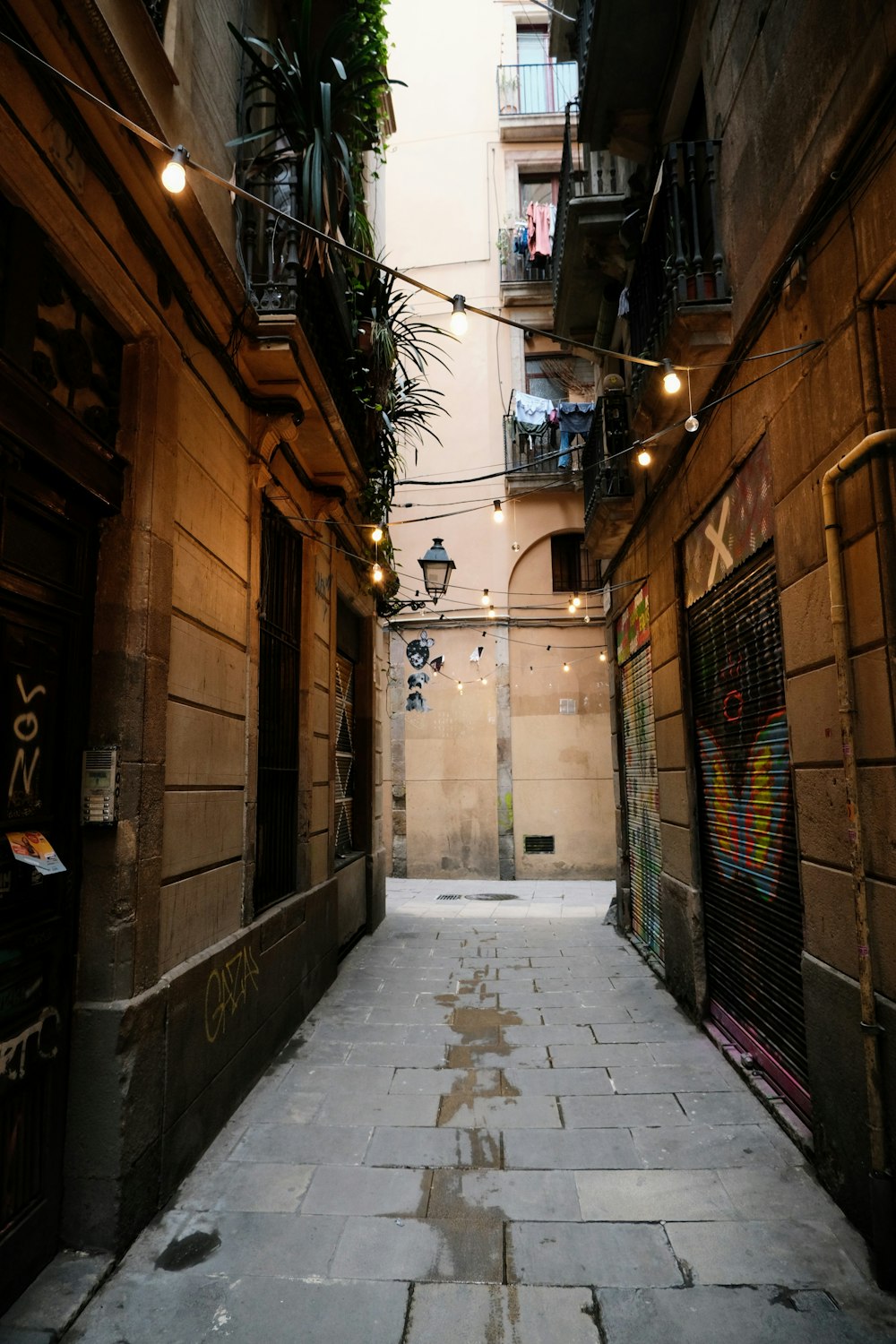 a narrow alley way with lights strung from the buildings