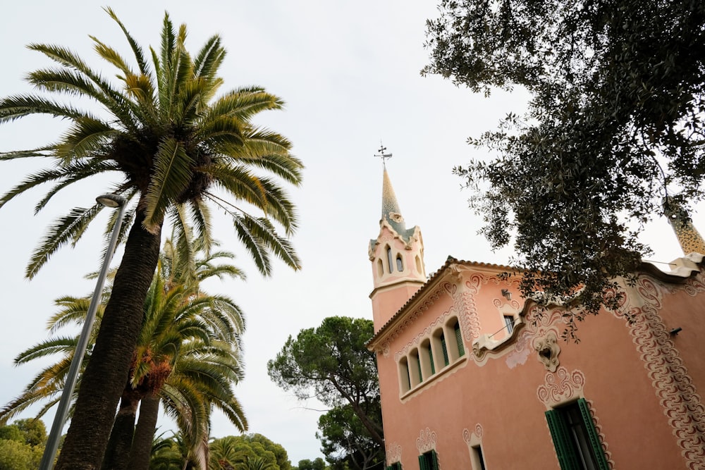 un edificio rosa con un campanario y una palmera