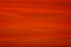 a red sky with a plane flying in the distance