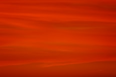 a red sky with a plane flying in the distance