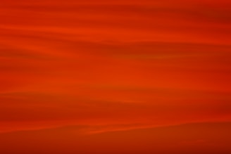a red sky with a plane flying in the distance