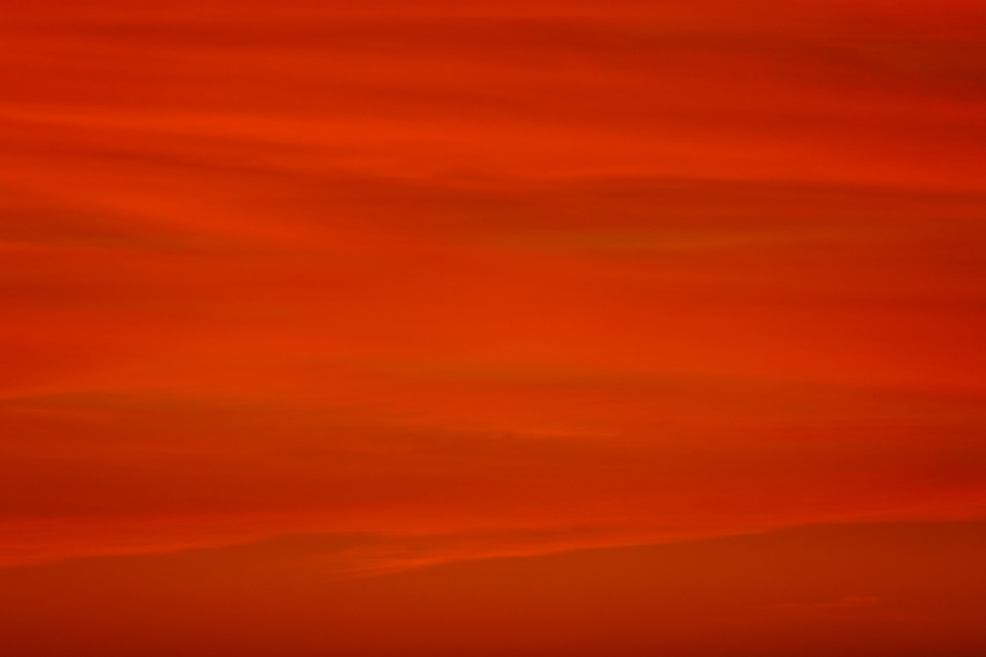 a red sky with a plane flying in the distance