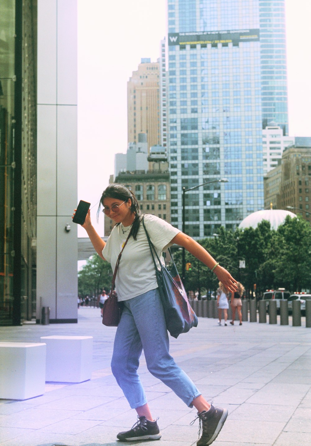 a woman walking down a street holding a cell phone