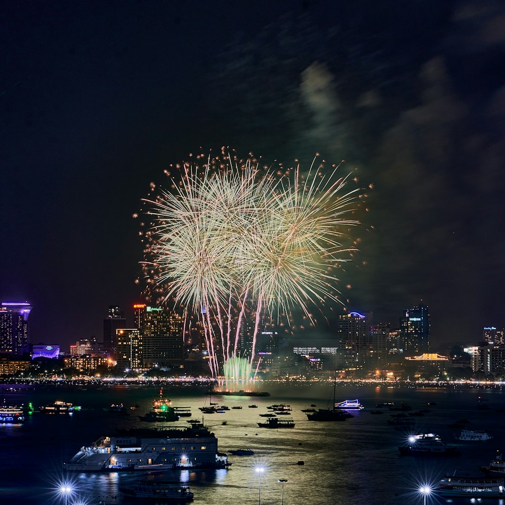 fireworks are lit up in the night sky over the water