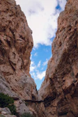 High cliffs and narrow walkways of Todra Gorge under a bright blue sky.