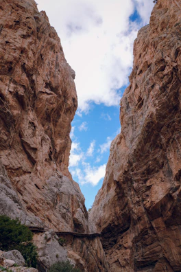 High cliffs and narrow walkways of Todra Gorge under a bright blue sky.
