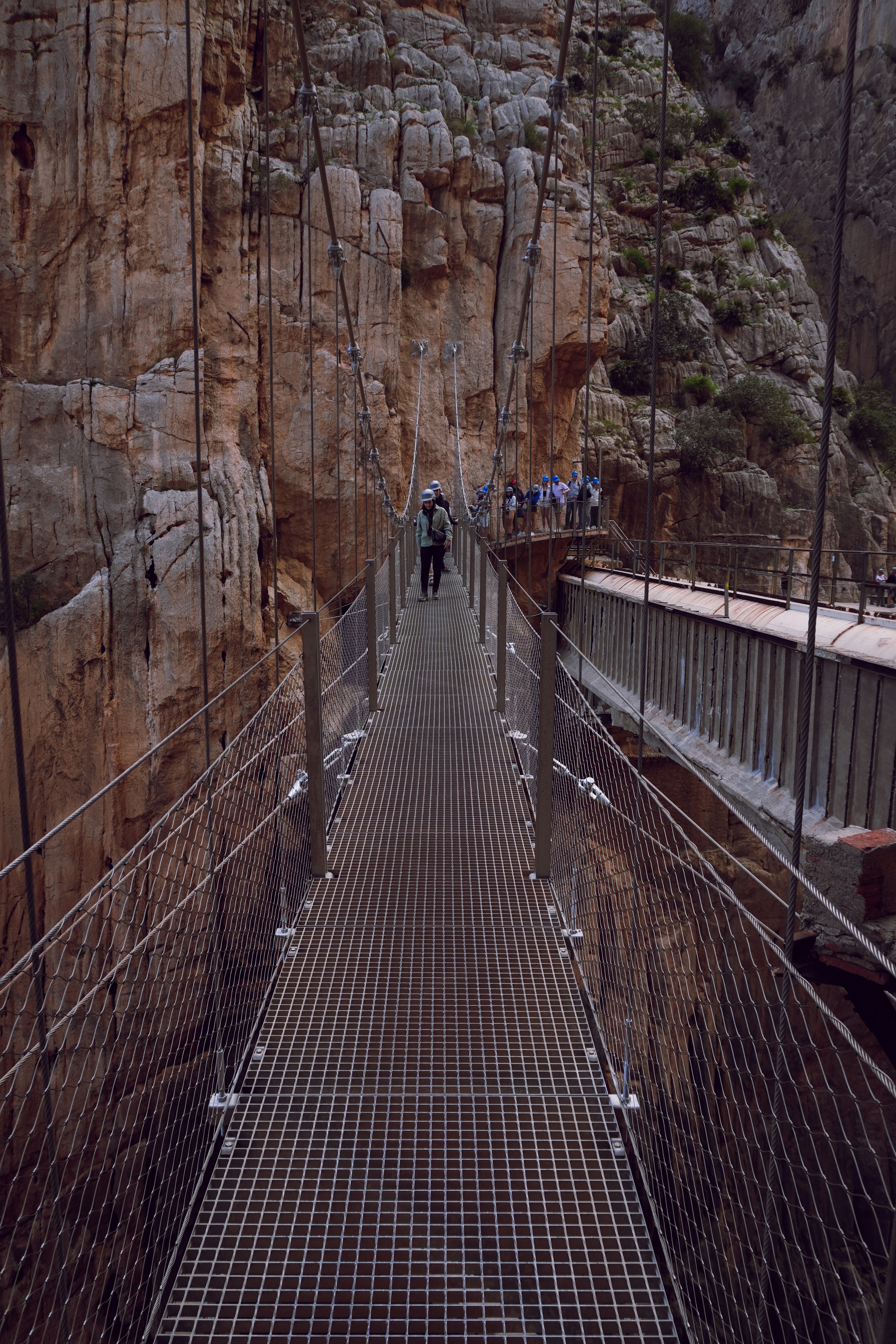 a man walking across a suspension bridge over a river