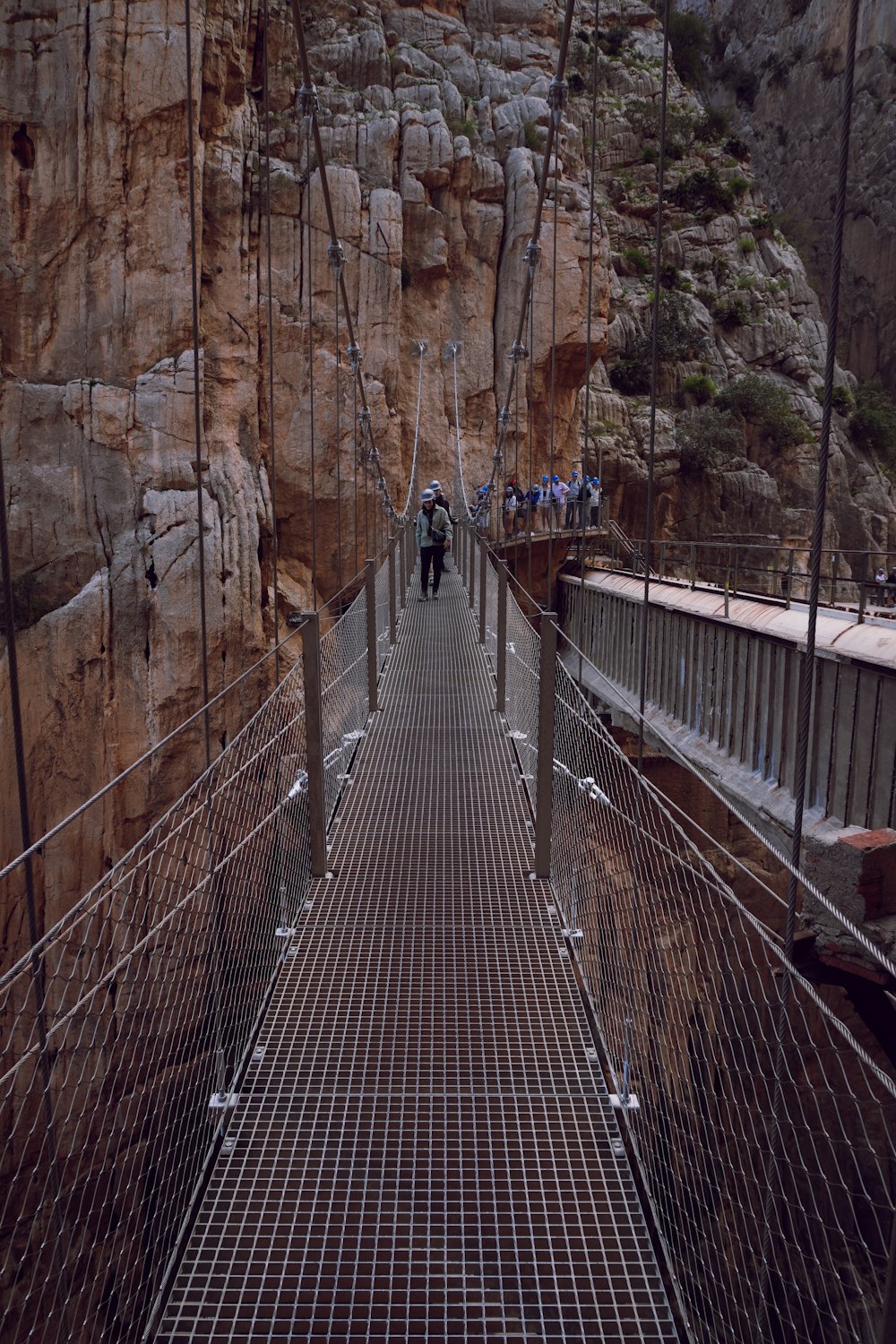 a man walking across a suspension bridge over a river