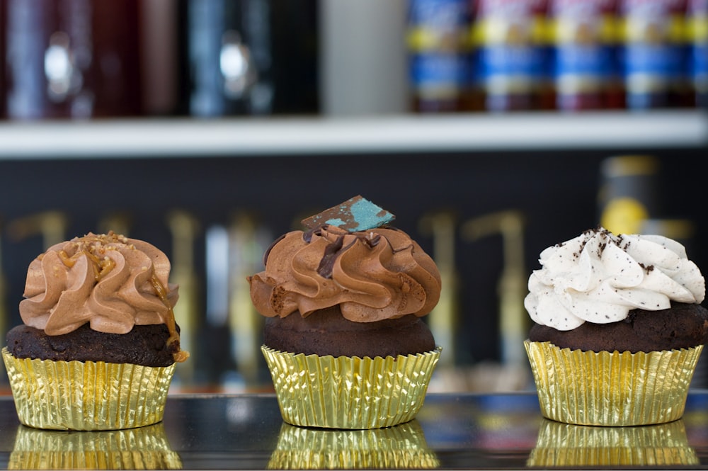 three cupcakes with chocolate frosting and sprinkles