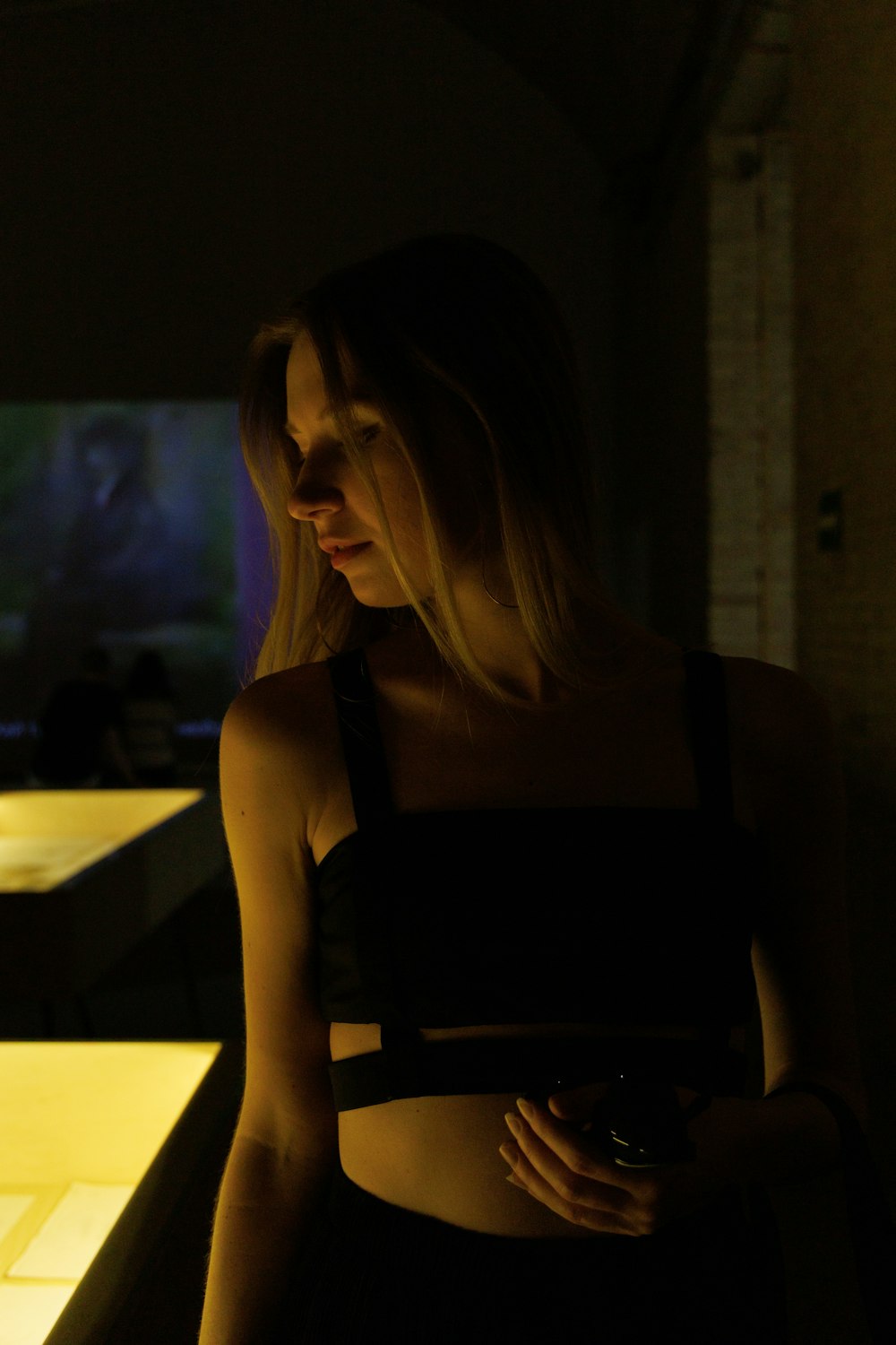 a woman standing in a dark room next to a counter