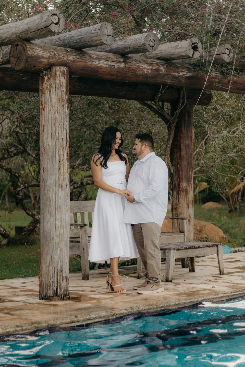 a man and woman standing next to a pool