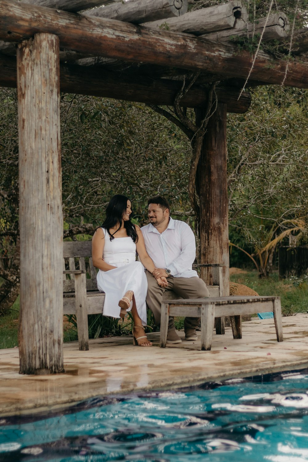 a man and woman sitting on a bench next to a pool