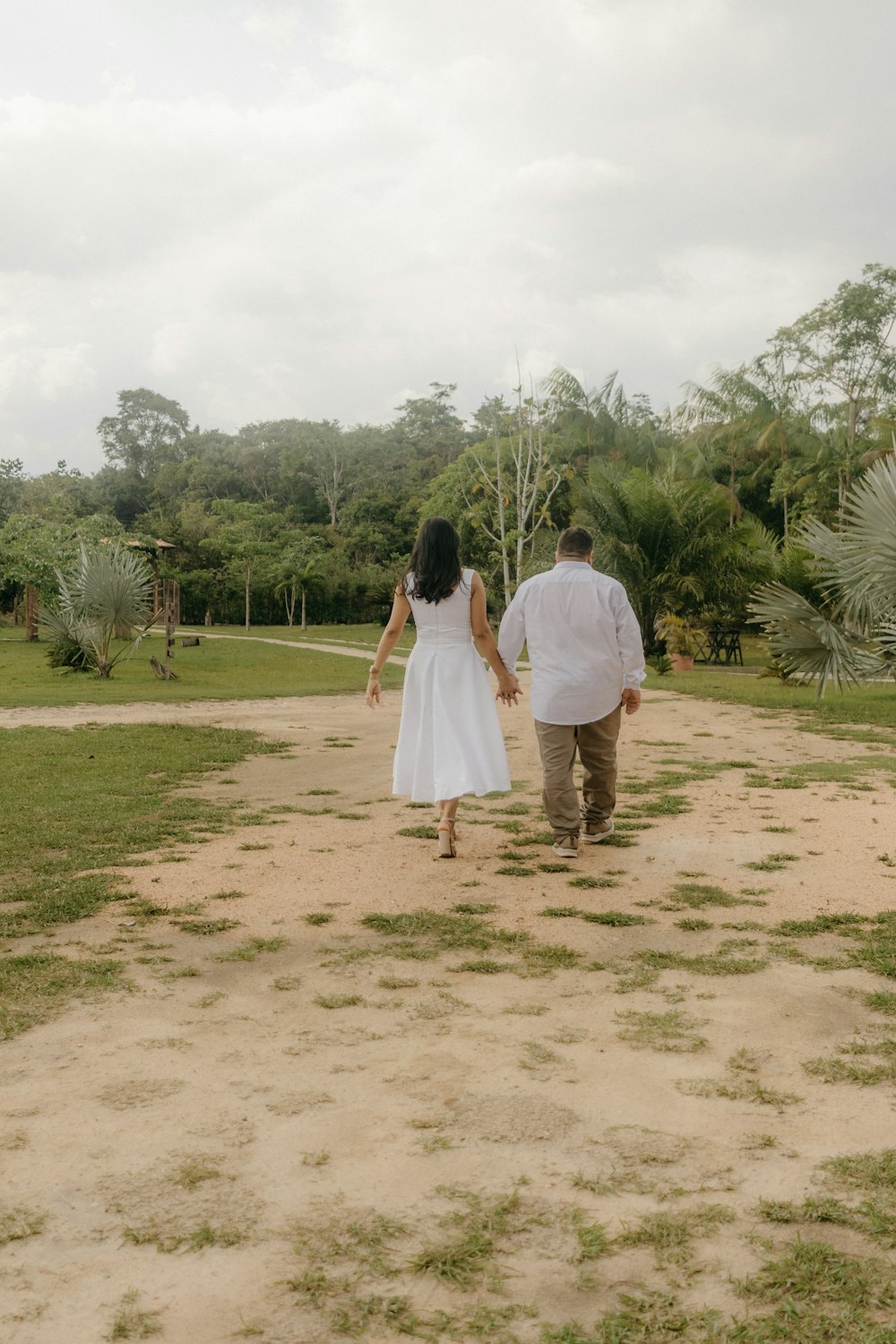 a man and a woman walking down a dirt road