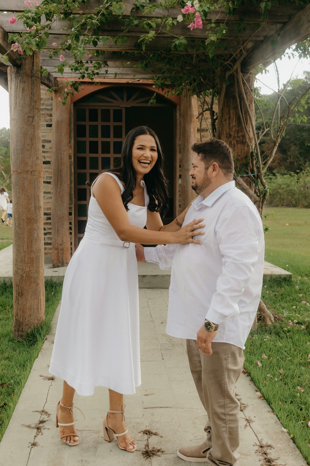 a woman in a white dress standing next to a man in a white shirt