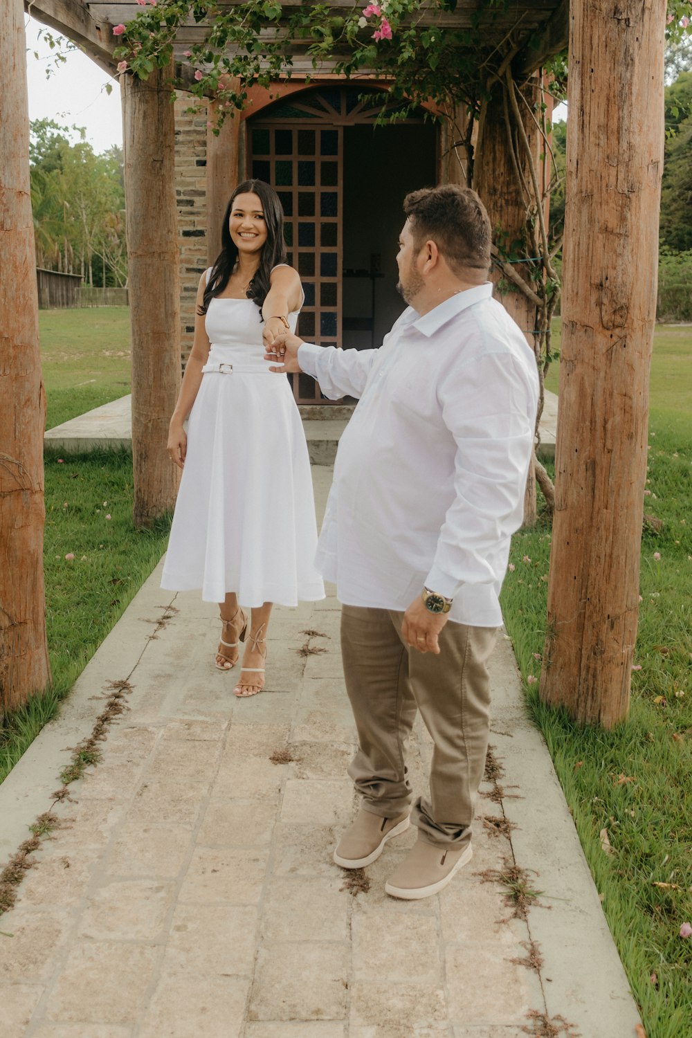 a woman in a white dress standing next to a man in a white dress