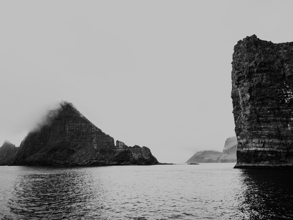 a black and white photo of a rock formation in the ocean