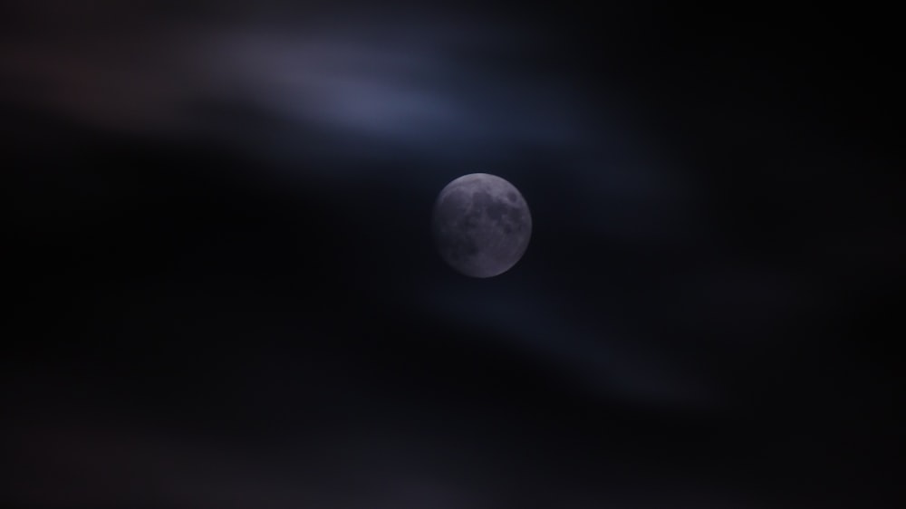 a full moon seen through the clouds in the night sky