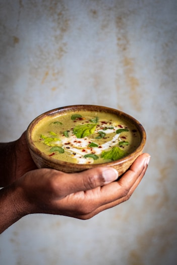 a person holding a bowl of soup in their hand