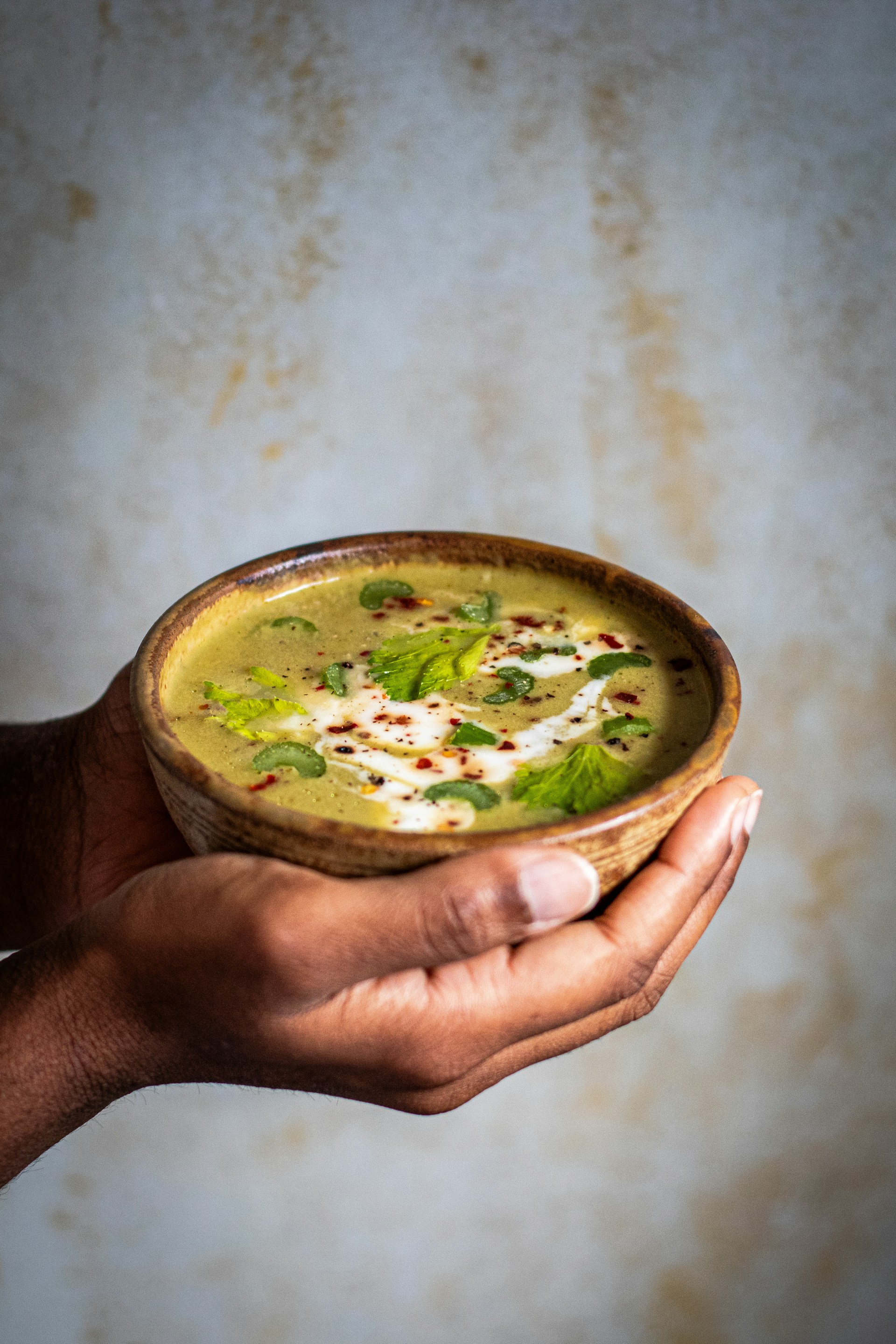 a person holding a bowl of soup in their hand