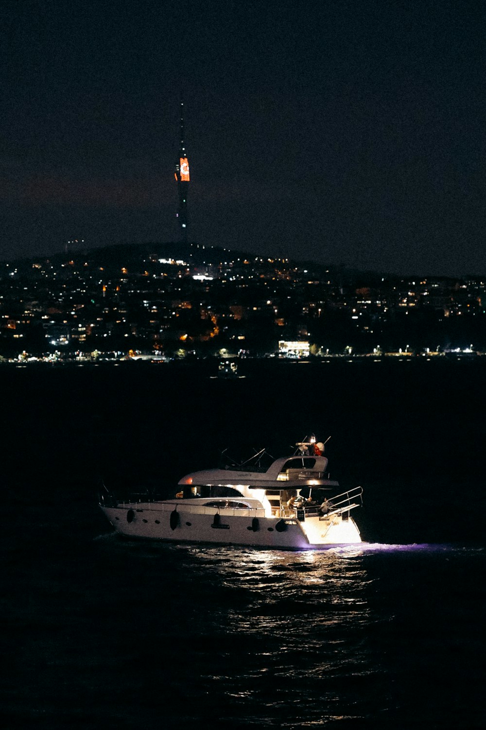 a boat in the water at night with a city in the background