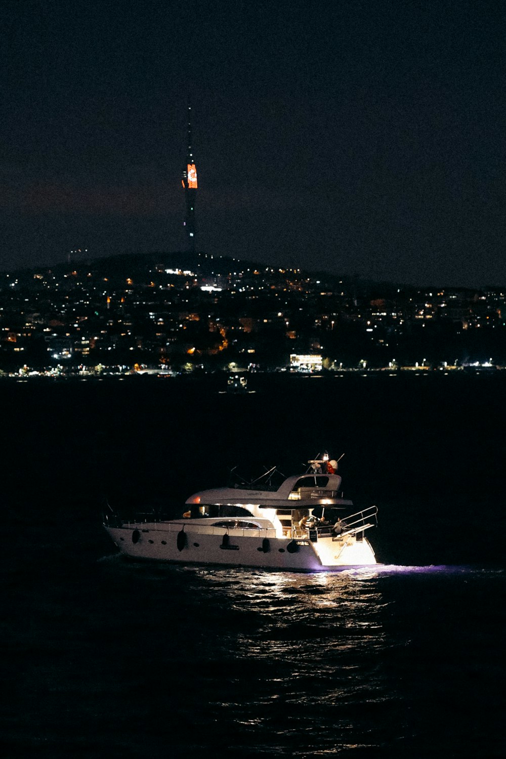 Un barco en el agua por la noche con una ciudad al fondo