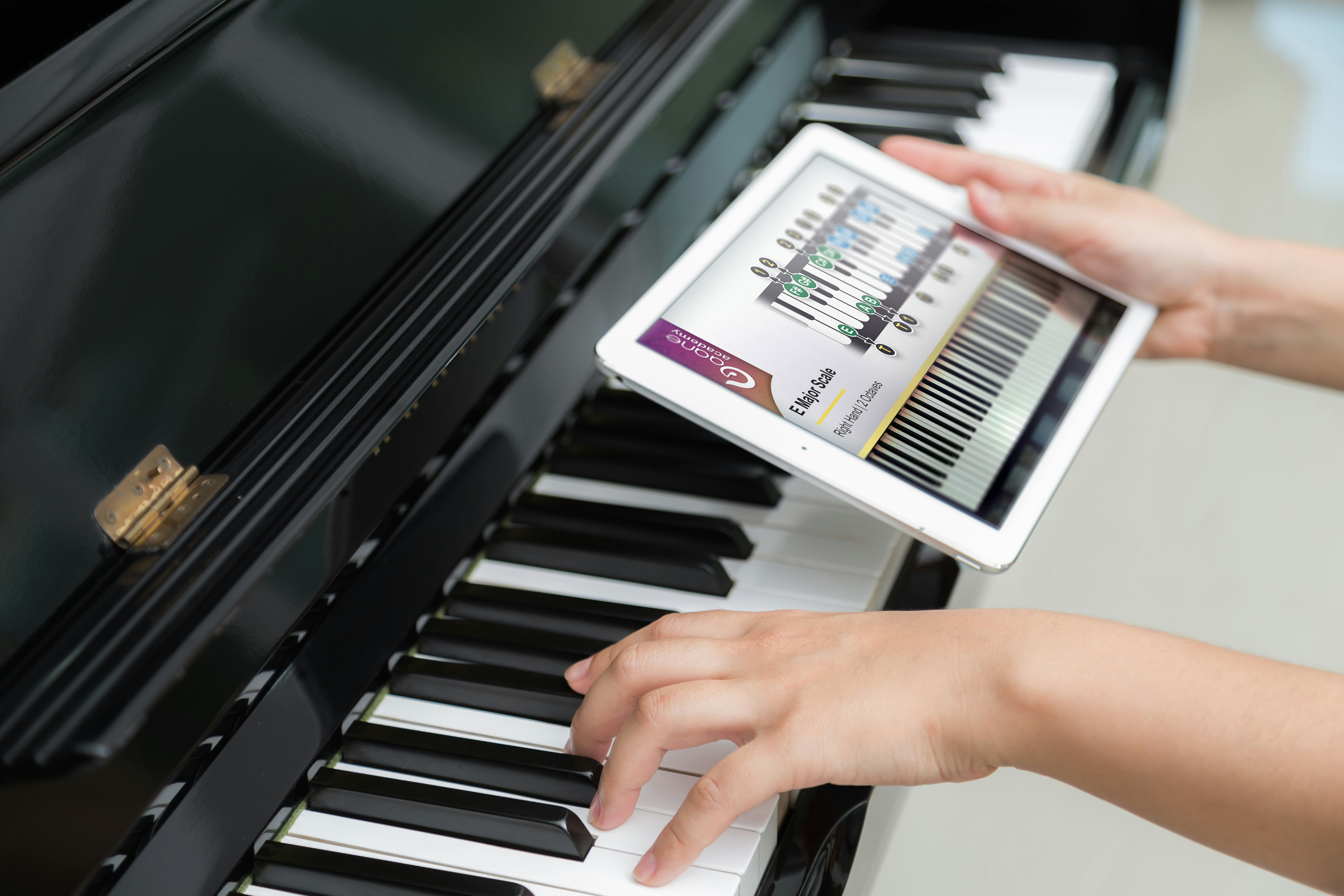 A person happily learning piano on a tablet with a digital keyboard