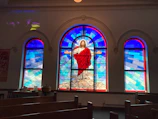 Close-up of a stained glass window depicting Don Bosco with warm colors.