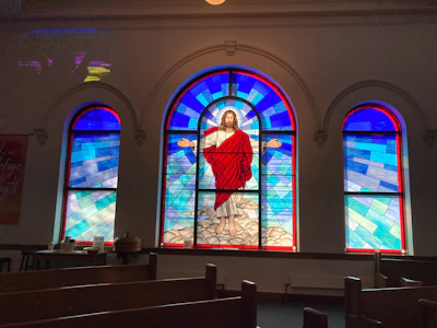 Close-up of a stained glass window depicting Don Bosco with warm colors.