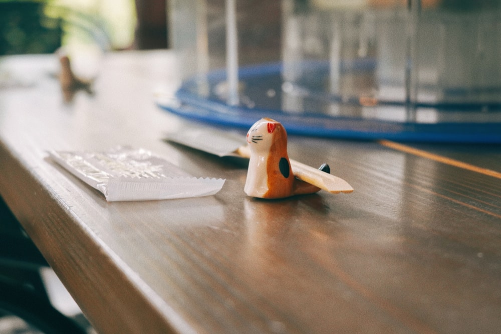 a toy cat sitting on a table next to a remote control