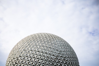 A large geodesic dome structure made up of triangular panels is pictured against a partly cloudy sky.