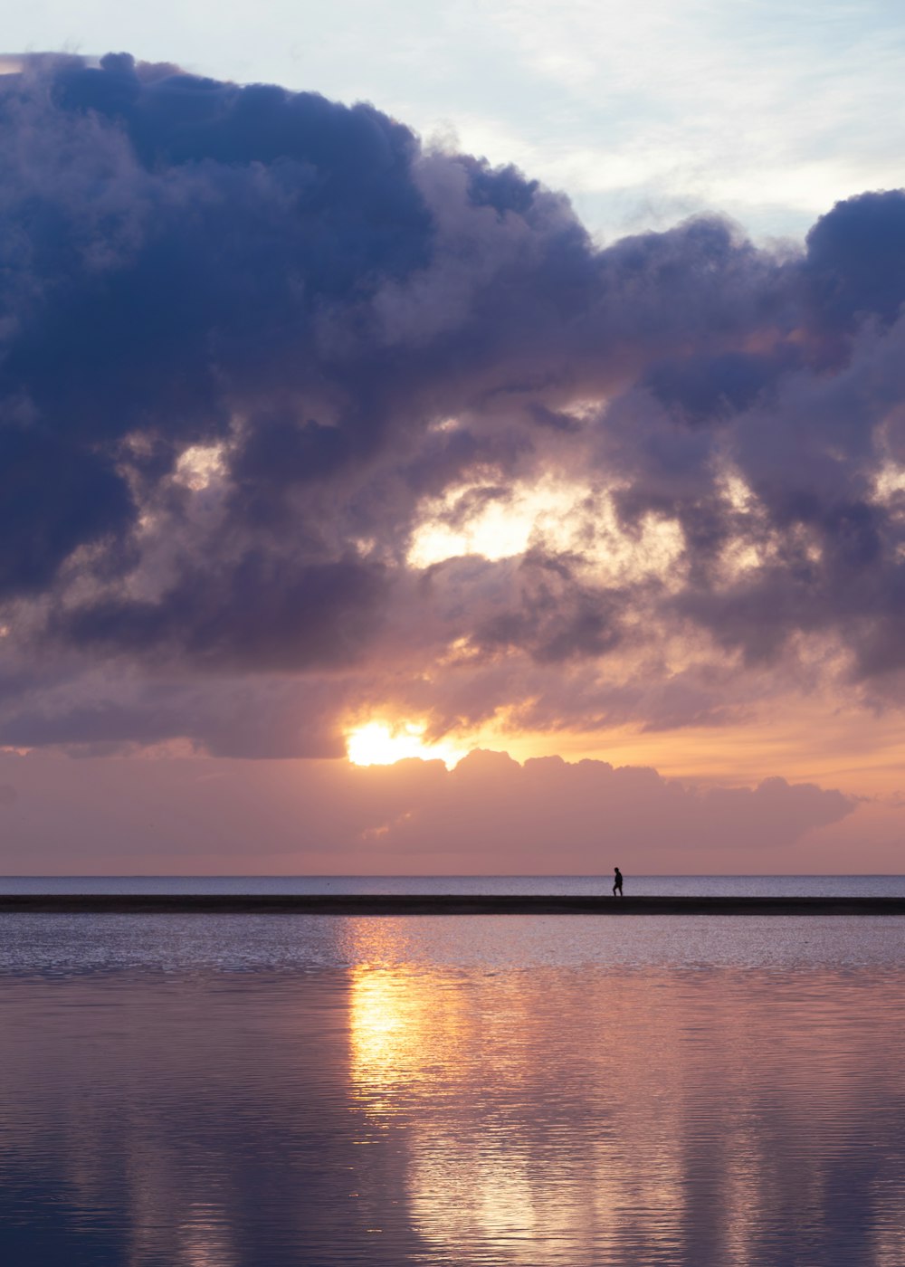 a person walking on a beach at sunset