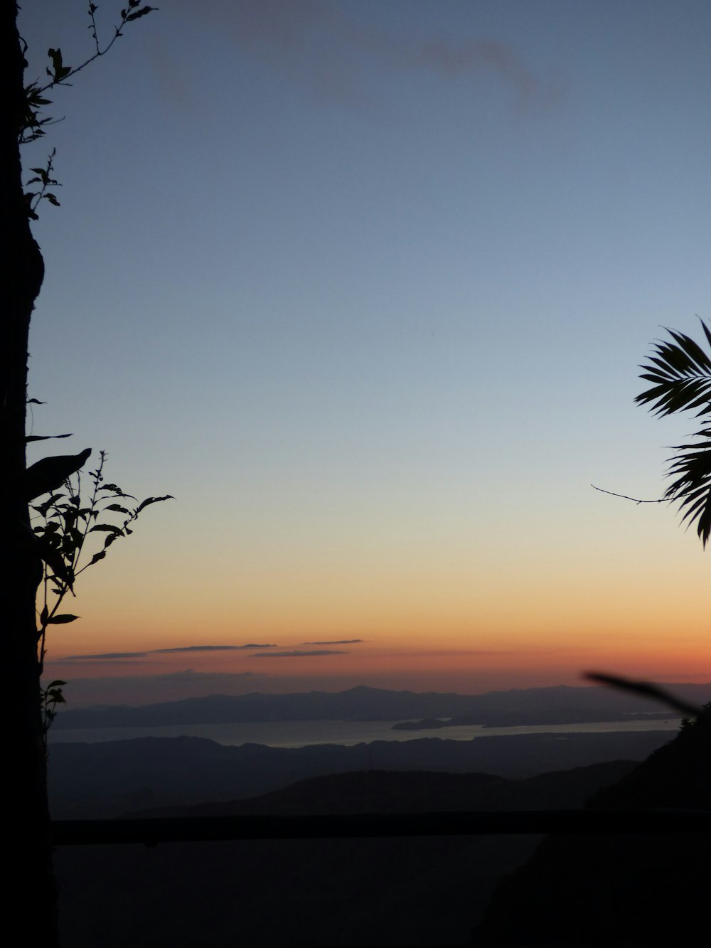 the sun is setting behind a tree with mountains in the background