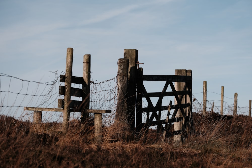 a wooden fence with barbed wire on top of a hill