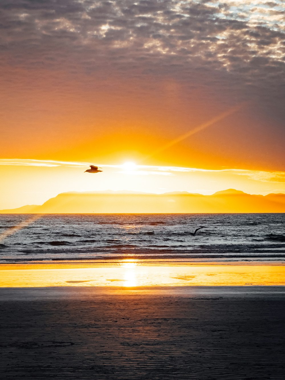 the sun is setting over the ocean on the beach