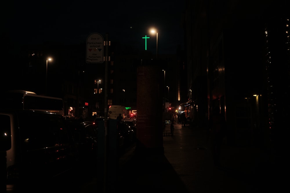 a city street at night with cars parked on the side of the road