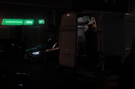 A driver helping a family load luggage into a van on a sunny street.