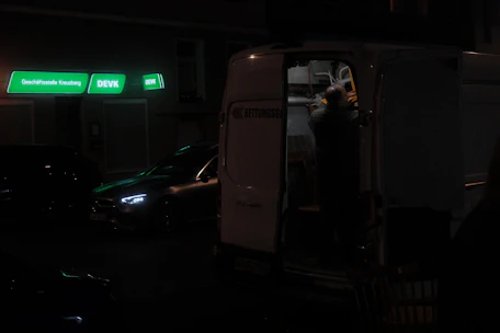 Driver loading bulky items into the cargo van at a busy storefront.