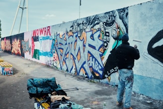 a man standing next to a wall covered in graffiti