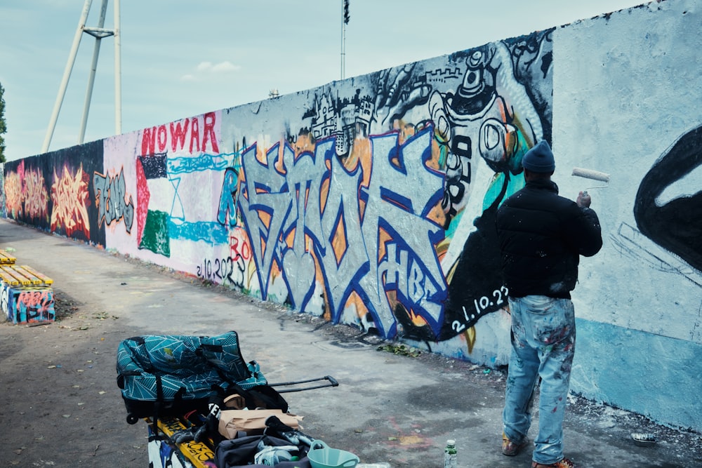 a man standing next to a wall covered in graffiti