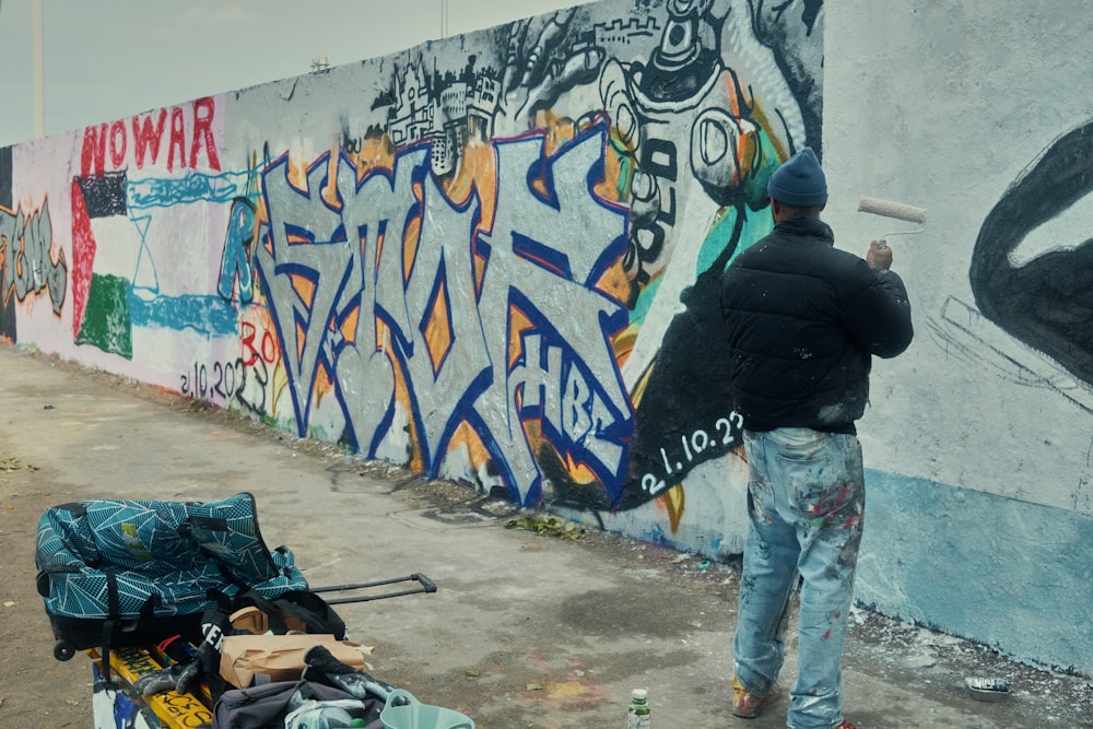 a man standing next to a wall covered in graffiti