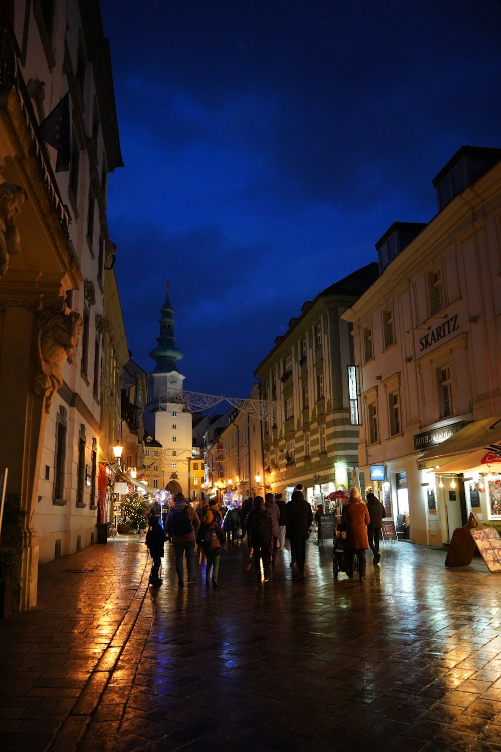 a group of people walking down a street at night