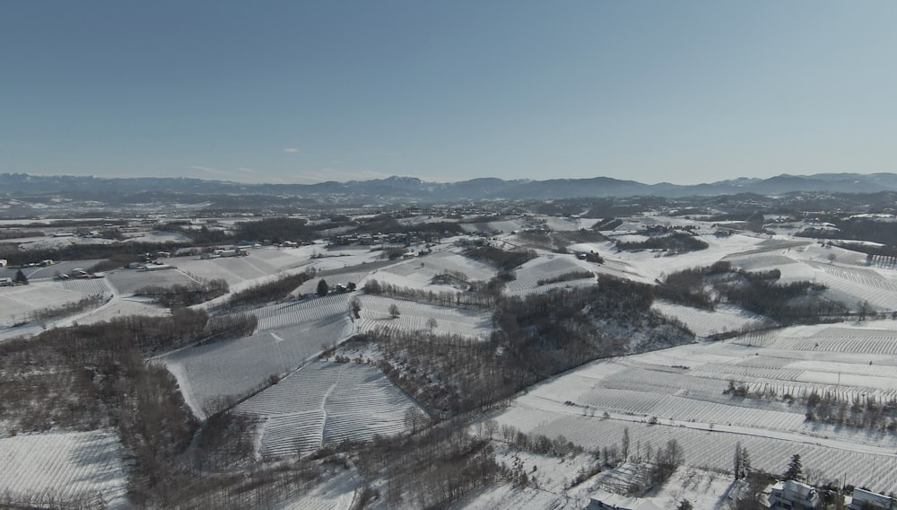 an aerial view of a snowy landscape with mountains in the background