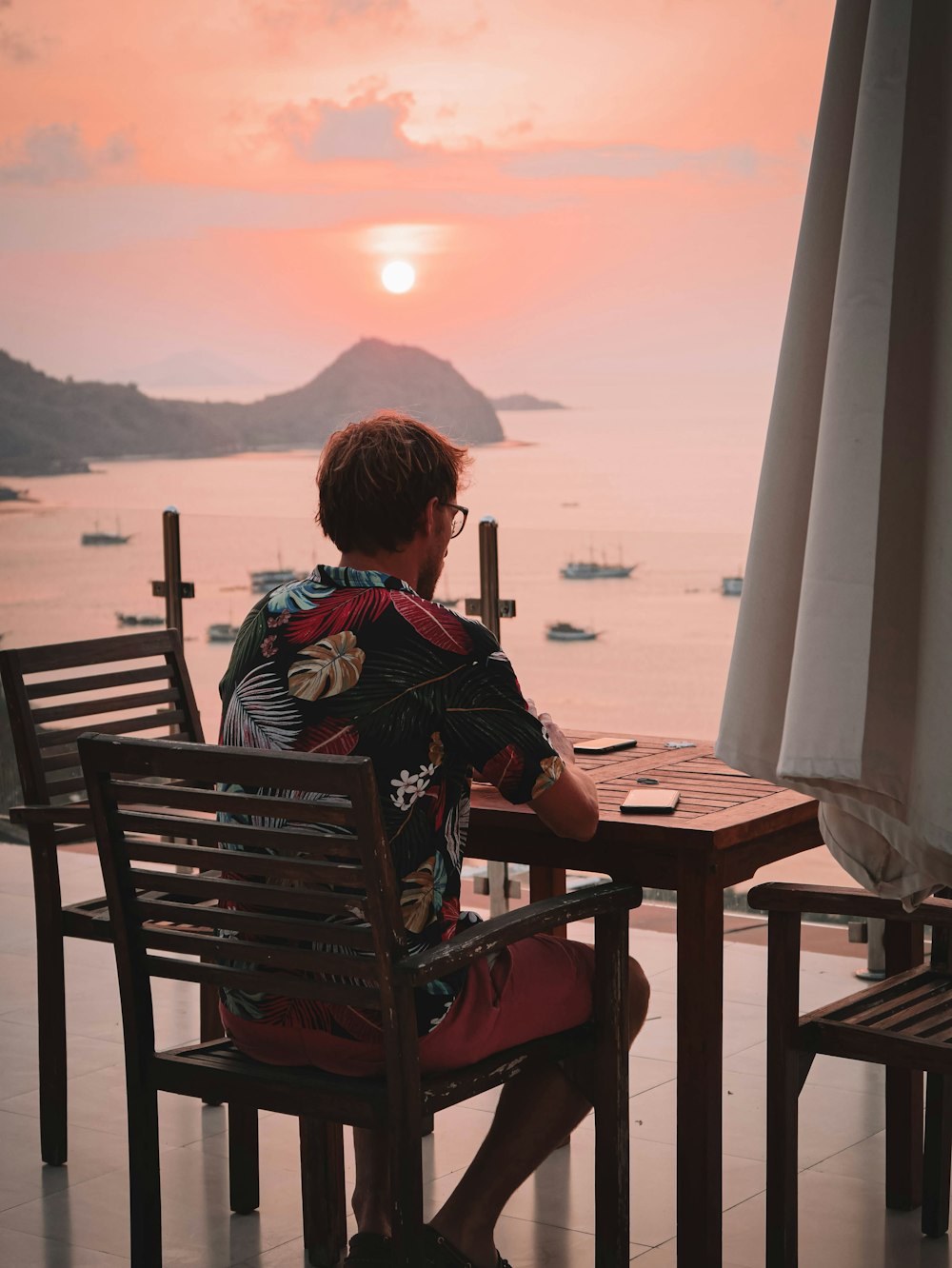 a man sitting at a table with a view of the ocean