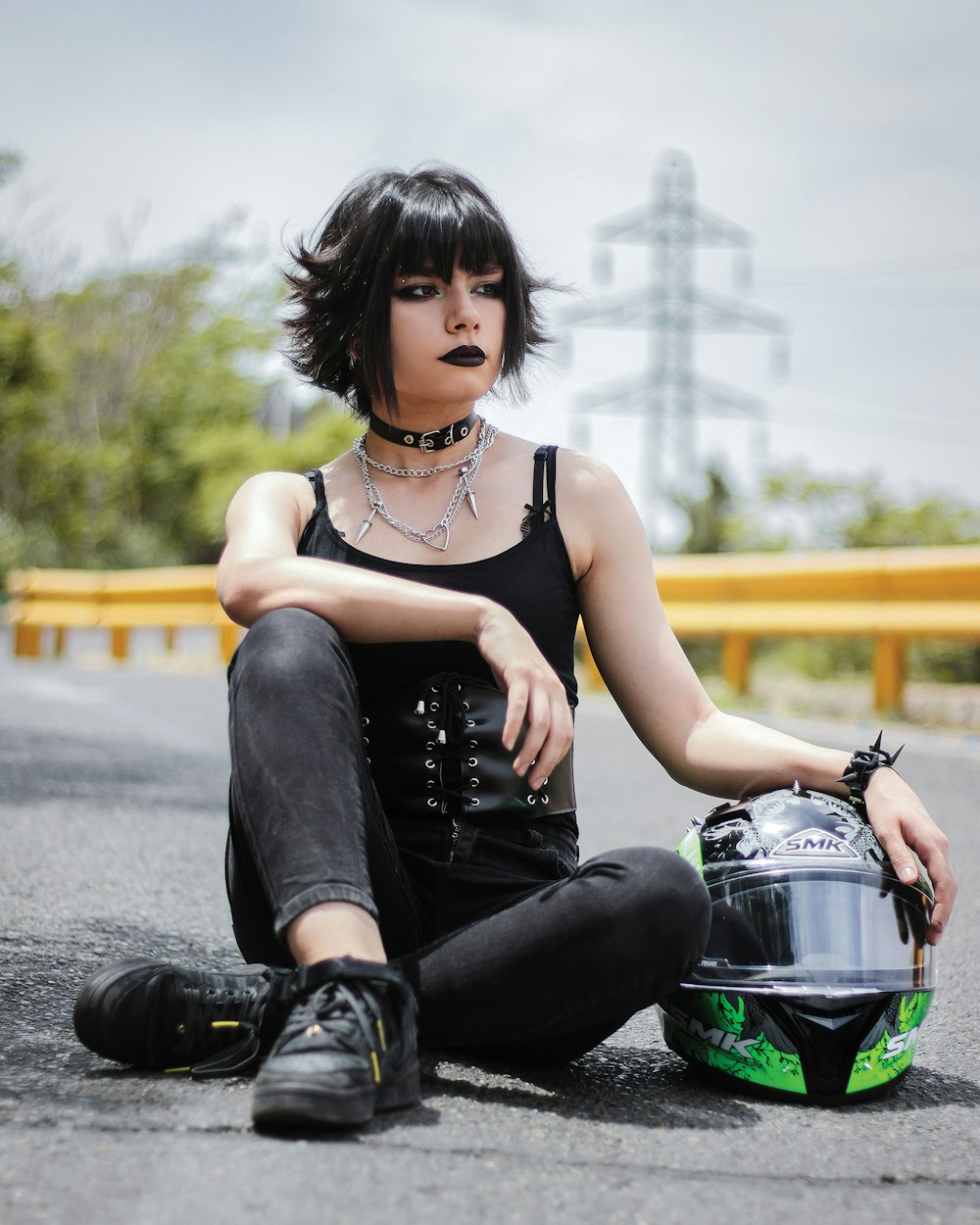 a woman sitting on the ground with a motorcycle helmet