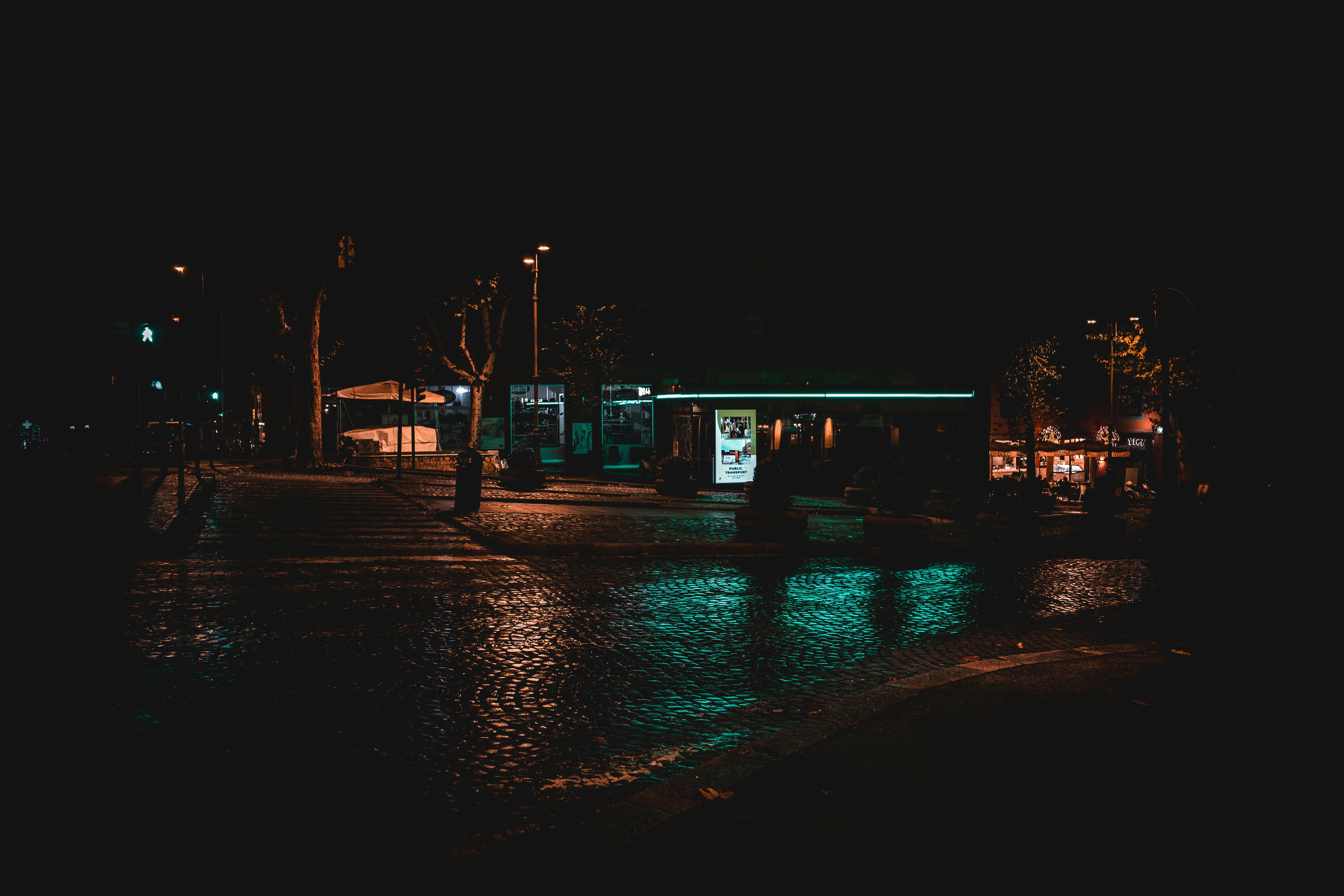 a wet street at night with a small building in the background